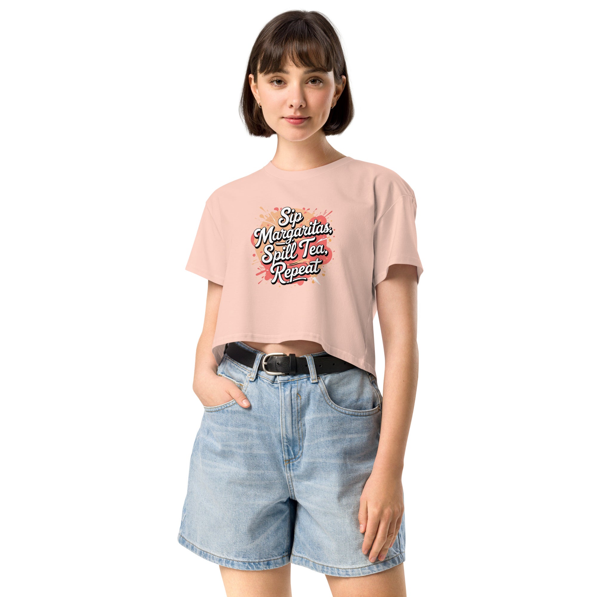 Model wearing Sip Margaritas, Spill Tea, Repeat cropped slogan T-shirt by Savage Cotton in pastel pink, styled with sunglasses and cocktail in hand